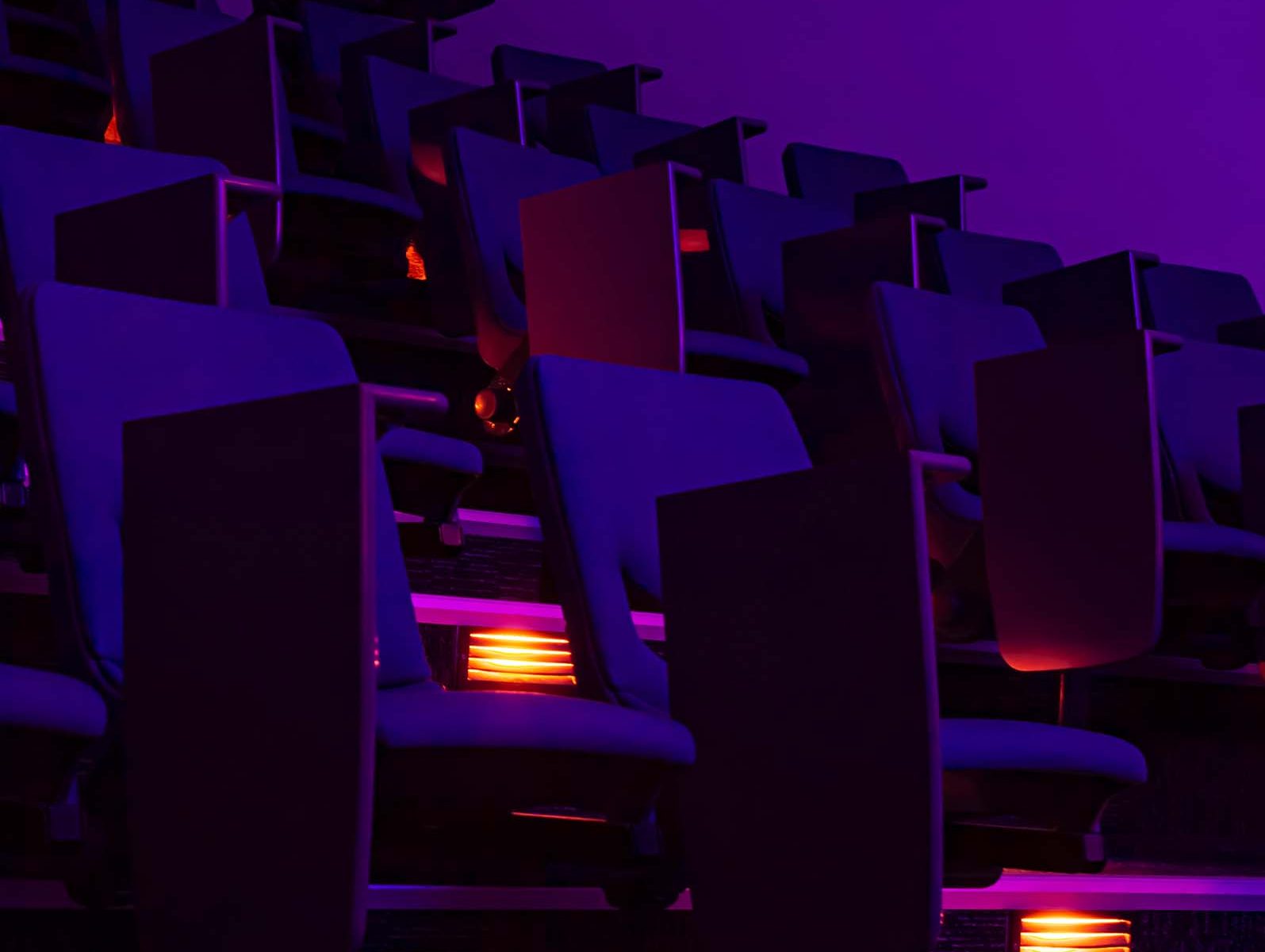 Dark lecture theatre with blue/purple and yellow lighting